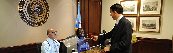 Photo showing CFTC receptionists processing a visitor's pass.
