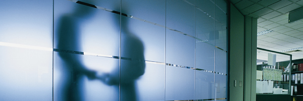 Photo showing the shadow of two people talking behind a glass wall. Photo by Getty Images.