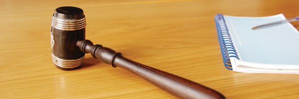 Photo showing a gavel and notebook at the head of a long conference table. Photo by Corbis Images.
